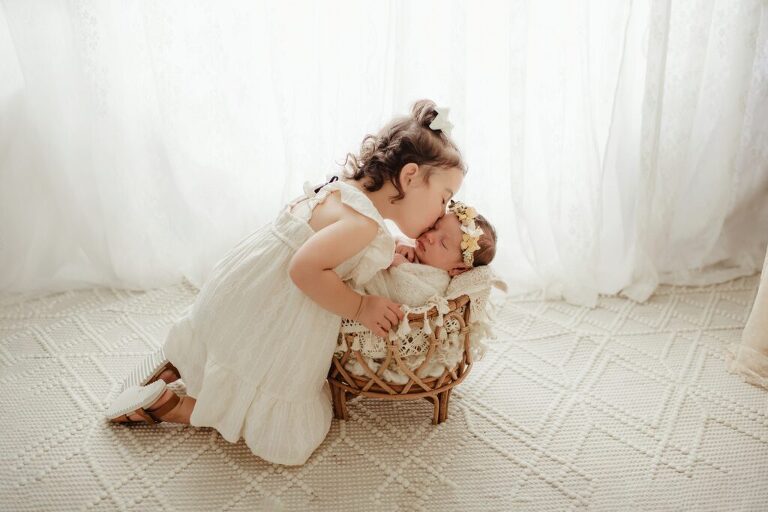Newborn girl with proud big sister in studio
