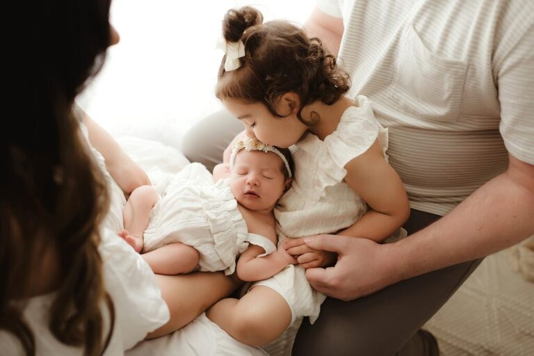 Big sister holding newborn baby sister